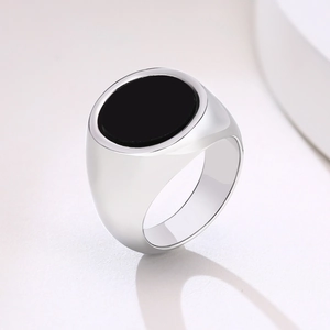 Macro view of men's stainless steel signet ring featuring a polished black onyx inlay