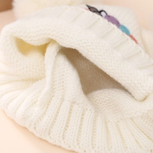 Detailed close-up of thick white knitted fabric texture and ribbed cuff on a winter hat