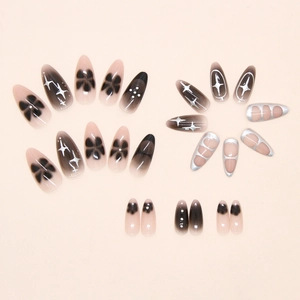 Detail of black and silver star patterned press-on nails with 3D metal star and bow designs