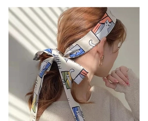 Detailed view of beige silk ribbon with cartoon cat print tied in a hair ponytail