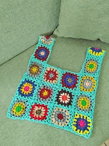 Detail view of handmade crochet tote bag featuring multi-color granny square floral patterns