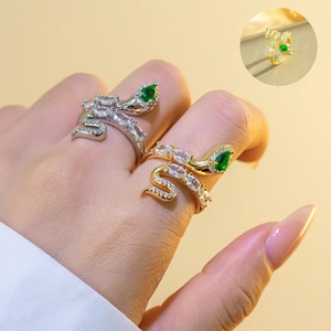 Detailed view of snake-shaped open rings with emerald green zircon eyes and crystal accents