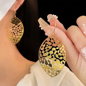 Large golden hollow leaf dangle earrings with intricate metal vein texture for women