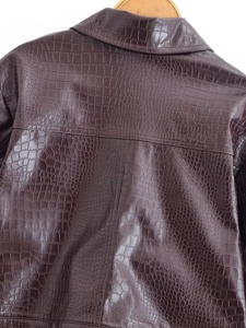 Detailed close-up of dark brown crocodile embossed leather texture on a vintage jacket
