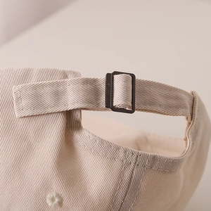 Dettaglio della fibbia regolabile in metallo sul berretto di cotone beige per bambini