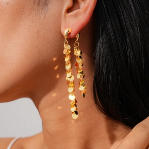 Vue rapprochée de boucles d'oreilles à paillettes plaquées or 18k portées par un mannequin