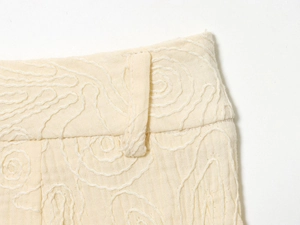 Détail du tissu en coton et lin crème montrant la taille et la broderie en spirale