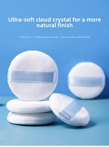 Detailed view of white crystal velvet powder puffs with blue ribbons for makeup setting