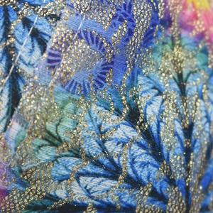 Gros plan d'un tissu jacquard coloré avec broderie de fil doré et détails de couture fins