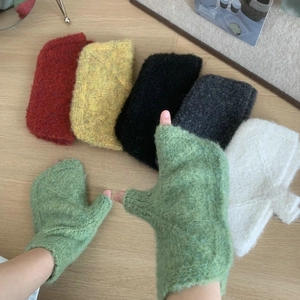 Close-up of knit fingerless gloves in various colors like green and yellow on wood