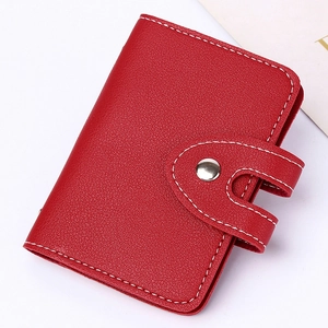 Close-up of red leather card holder featuring metal snap button and white stitching detail
