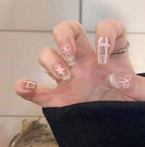 Detailed view of pink cat-eye press-on nails with bow, star patterns and pearls
