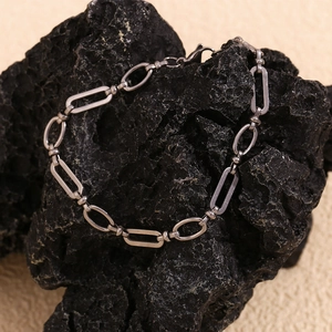 Detail of silver stainless steel mixed link anklet on black volcanic stone
