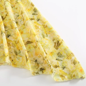 Detailansicht von gelbem Chiffonstoff mit Blumenmuster, weichen Falten und feiner Nahtführung