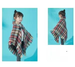 Detailed view of kids hooded plaid cape with tassel hem and horn button closure
