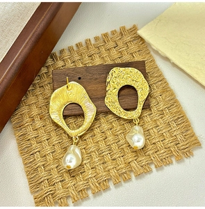 Detail of vintage Baroque pearl earrings with hammered hollow gold metal texture