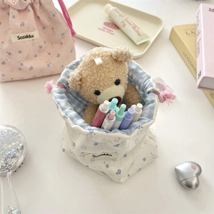 Floral drawstring pouches with tassel details and plush bear in a cozy scene