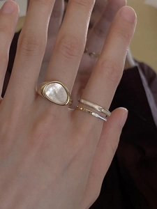 Detail of gold stacking rings featuring a shell inlay and a Queen engraved band