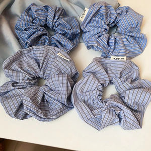 Detailed macro of assorted blue and white checkered fabric scrunchies with brand labels