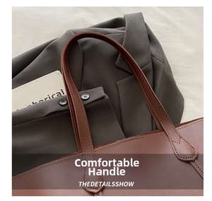 Detail shot of brown leather tote bag handle showing fine stitching on grey blazer