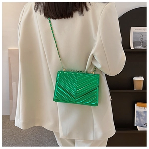 Detail of a metallic bright green crossbody bag with V-quilted faux leather and gold chain