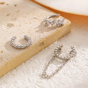 Detalle del set de 3 earcuffs plateados con circonitas y cadena fina sobre base de piedra