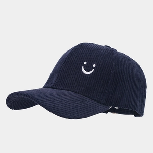 Dettaglio del tessuto in velluto a coste blu navy e del ricamo smiley sulla cappellino