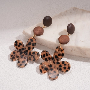 Détail de boucles d'oreilles fleurs en résine léopard et disques de bois sur marbre