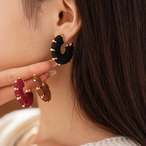 Macro detail of U-shaped striped earrings with golden beads and colorful thread winding