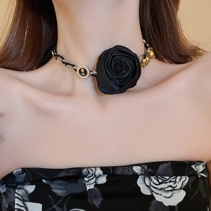 Dettaglio choker con grande rosa in raso nero, catena d'argento e ciondolo dorato a rilievo