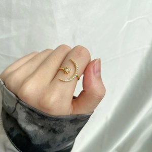 Macro shot of an adjustable gold star and moon ring with pavé-set crystals
