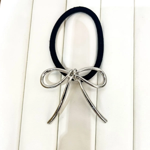 Close-up of a black elastic hair tie with a minimalist silver metal bow charm