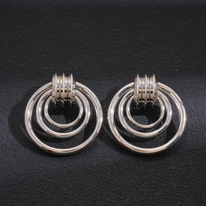Macro detail of silver geometric hollow circular earrings on a textured black surface