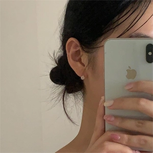 Close-up of minimalist small flower stud earring in 925 sterling silver on ear