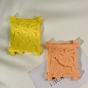 Makroansicht gelber und rosa Silikonformen mit Schmetterlings- und Blumenrelief