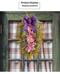 Detail of pink and white hydrangea swag wreath with a purple silk bow on a green door