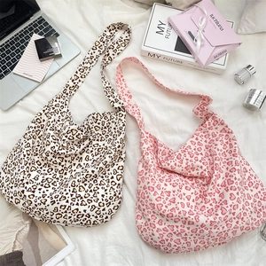 Flat lay of leopard heart print canvas tote bags with lifestyle accessories on white sheets