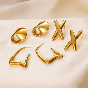 Three pairs of geometric 18K gold plated stainless steel earrings on beige silk fabric