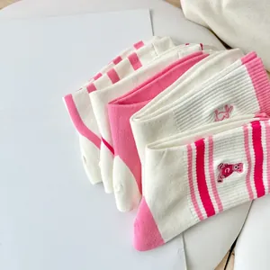 Detail of pink striped knit socks with cute bear embroidery and ribbed cotton texture