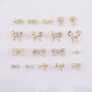 Détails macro de breloques nœuds dorés pour nail art avec perles et strass brillants