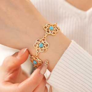 Close-up of vintage gold hollow flower bracelet with turquoise and rhinestones on model