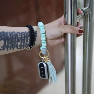 Close-up of mint green silicone beaded bracelet key ring with LOVE charm on a hand