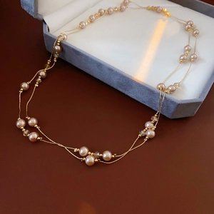 Detail view of multi-layer champagne faux pearl and crystal necklace with gold wires