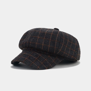 Detail of grey and orange plaid newsboy cap showing tweed texture and top button