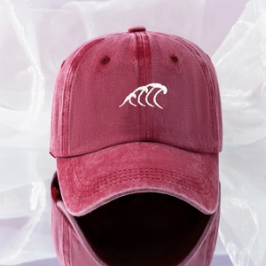 Close-up of white wave embroidery on a washed cotton burgundy baseball cap