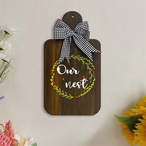 Detail of wooden cutting board wall decor with Our nest text and gingham bow