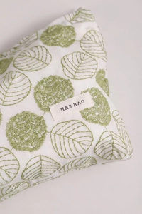 Close-up of white linen cosmetic bag featuring detailed green floral embroidery work