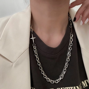 Detail shot of a silver layered cross necklace on a male model with stylish street style