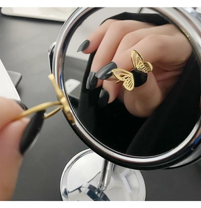 Detailed mirror reflection showing the intricate hollow golden butterfly ring on a finger