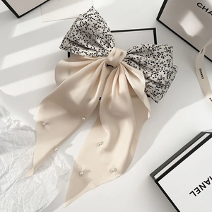 Close-up of vintage floral bow hair clip with pearls and long flowing cream ribbons